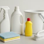Assorted cleaning supplies arranged on a neutral background